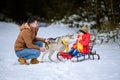 Father with daughter on a walk in the woods, daughter sitting on a sleigh and playing with a husky, a cheerful family with a dog Royalty Free Stock Photo