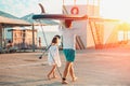 Father and daughter are walking along the beach. Man holding a sup board. Back view. Sunset light. Summer family vacation Royalty Free Stock Photo