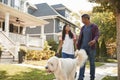 Father And Daughter Walking Dog Along Suburban Street Royalty Free Stock Photo