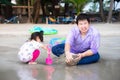 The father and daughter were enjoying the sand on the beach. Cute girl is digging sand with a pink plastic shovel. Royalty Free Stock Photo