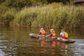 Father and daughters in life jackets paddeling in a dugout canoe