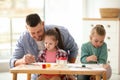 Father and daughters painting at table. Playing with children