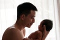 Father day bonding concept with newborn baby nursing. Father is playing and talking with newborn baby beside window. Single Dad co