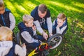 Father day. A large friendly family father and sons together actively relax in the fresh air. Dad teaches sons to repair bicycles