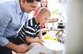 Father with down syndrome son indoors in kitchen, washing dishes. Royalty Free Stock Photo