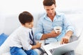 Father drinking coffee and teaching son how to use notebook. Royalty Free Stock Photo