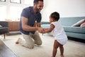 Father Encouraging Baby Daughter To Take First Steps At Home Royalty Free Stock Photo