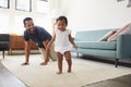 Father Encouraging Baby Daughter To Take First Steps At Home