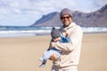 Father enjoying pure nature holding and playing with his infant baby boy son in on windy sandy beach of Famara