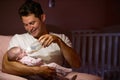 Father Feeding Baby With Bottle In Nursery