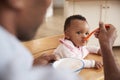 Father Feeding Baby Daughter In High Chair