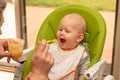 Father feeding baby with spoon full of apple puree. Baby first solids. Weaning