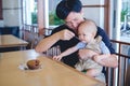 Father feeding food bakery to Cute little Asian 1 year old toddler baby boy child with spoon at the restaurant Royalty Free Stock Photo