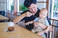 Father feeding food bakery to Cute little Asian 1 year old toddler baby boy child with spoon at the restaurant Royalty Free Stock Photo