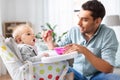 Father feeding happy baby in highchair at home Royalty Free Stock Photo