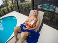 Father feeding his adorable son a bottle while sitting by the swimming pool Royalty Free Stock Photo