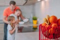 A father feeds his daughters in the kitchen on a background of fruits