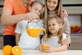 A father feeds his daughters in the kitchen on a background of fruits and juce