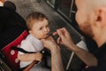 A father feeds his little son. The child eats and looks at the camera. Baby food concept. Soft focus blurred and noise effect