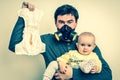 Father with gas mask is holding dirty diaper and little baby Royalty Free Stock Photo