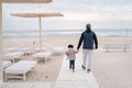 Father with girl child walking to sea beach in autumn