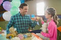 Father and girl toasting their tea cups while playing with toy kitchen set