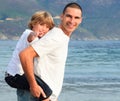 Father giving his son piggyback ride on the beach Royalty Free Stock Photo