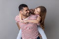 Father giving piggyback ride for his charming daughter, smiling girl looking at her daddy with love. Royalty Free Stock Photo