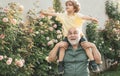 Father giving son ride on back in park. Happy grandfather giving grandson piggyback ride on his shoulders and looking up Royalty Free Stock Photo