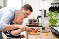 Father with happy down syndrome son indoors in kitchen, chopping apple. Royalty Free Stock Photo