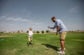 Father has fun and teaches his son to play golf on the green grass Royalty Free Stock Photo
