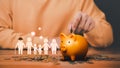 Father is head of the family, putting coins on piggy bank with family icon on the table.