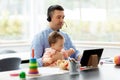 Father in headset working at home office with baby