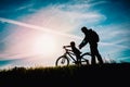 Father help little daughter to ride bike at sunset nature Royalty Free Stock Photo