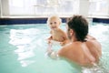 Father Helping Baby Swim in Indoor Hotel Swimming Pool Royalty Free Stock Photo