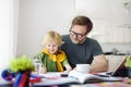 Father helping child do his homework at home. Homeschooling, distance learning, online studying, remote education for kids during Royalty Free Stock Photo