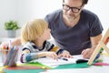 Father helping child do his homework at home. Homeschooling, distance learning, online studying, remote education for kids during Royalty Free Stock Photo