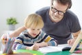 Father helping child do his homework at home. Homeschooling, distance learning, online studying, remote education for kids during Royalty Free Stock Photo