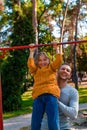 Father helping daughter to pull up on the uneven bars at the playground. Healthy family concept