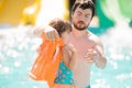 Father helping his cute toddler daughter with her life jacket in outdoors swimming pool in water park aquapark Royalty Free Stock Photo