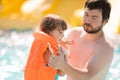 Father helping his cute toddler daughter wuth her life jacket in outdoors swimming pool in water park aquapark Royalty Free Stock Photo