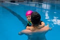 Father helping his little daughter overcome fear of swimming. Young father teaching his fearful daughter how to swim in