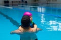 Father helping his little daughter overcome fear of swimming. Young father teaching his fearful daughter how to swim in