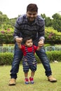 Father helping his toddler son to walk inside a garden, Pune, Maharashtra