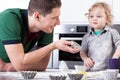 Father helping son baking muffins