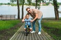 father helping son riding small bike on road