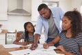 Father Helping Two Daughters Sitting At Table Doing Homework