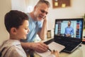 Father helps his son with home work. Boy in video conference with teacher on laptop at home