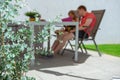 Father and his adorable happy daughter playing  with tablet on terrace under the sun shade with eucalyptus bush on foreground Royalty Free Stock Photo