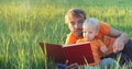 Father and his cute toddler son read book together in summer field. Authentic lifestyle image. Parenting concept. Copy space Royalty Free Stock Photo